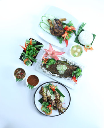 Grilled sea bass fish, chicken, squid  with vegetables on white background, Thai style food.の写真素材