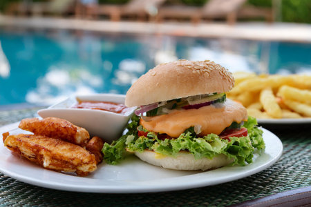 Hamburger and french fries on the table at the swimming pool. It's snack menu while you resting at the resort.の写真素材