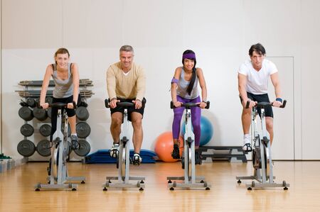 Happy active people exercising with bicycles in a gym. Front viewの写真素材