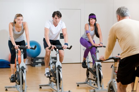 Fitness instructor with his class of spinning cycler at gymの写真素材