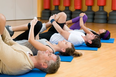 Happy fitness people class in a row doing some aerobic stretching after workout at gymの写真素材