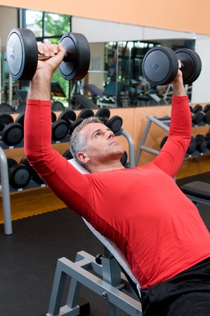 Mature man lifting dumbells at fitness gymの写真素材