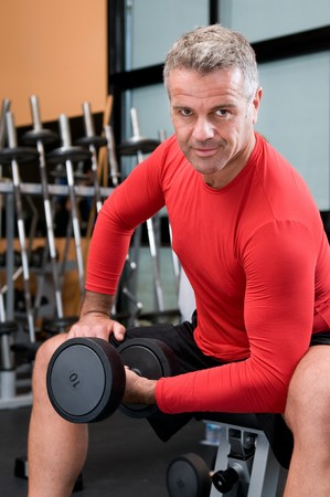 Happy satisfied mature man lifting weights at gymの写真素材