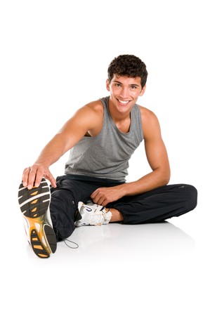 Happy smiling young fitness man sitting and making stretching exercises after gym isolated on white backgroundの写真素材
