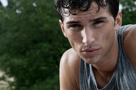 Young exhausted latin man looking at camera during a break of his outdoor jogging trainingの写真素材