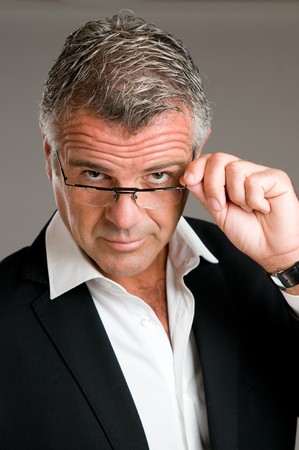 Mature man holding and putting on a pair of glasses with satisfactionの写真素材