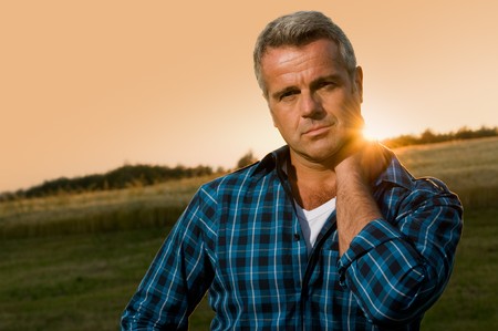 Mature man relax and looking at camera with satisfaction in the wonderful light of the sunsetの写真素材