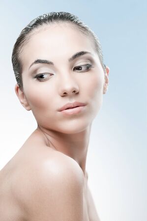 Beautiful female model looking away over a light blue background, professional beauty makeup and retouchingの写真素材