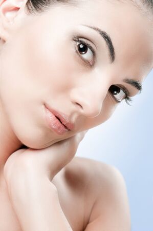 Beautiful model touching her soft skin over a light blue background, professional beauty makeupの写真素材