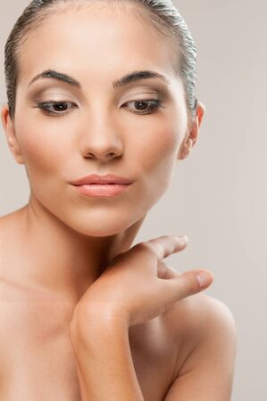 Beautiful female model looking down over a gray background, professional beauty makeup and retouchingの写真素材