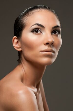 Beautiful female model with professional fashion makeup posing over gray backgroundの写真素材
