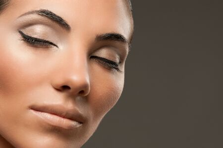 Closeup shot of beautiful female model with professional fashion makeup posing over gray backgroundの写真素材