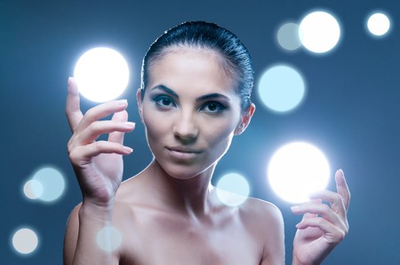 Beautiful fairy female model holding sphere of light on her hands, professional beauty makeupの写真素材