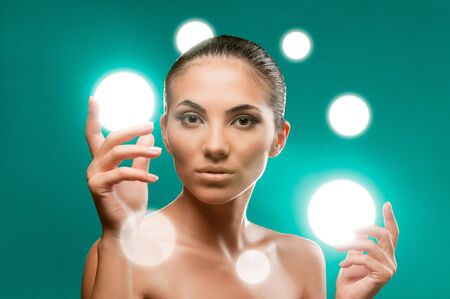 Beautiful fairy female model holding spheres of light on her hands, professional beauty makeupの写真素材