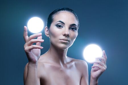 Beautiful fairy female model holding two spheres of light on her hands, professional beauty makeupの写真素材