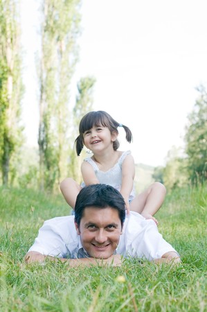 Sweet cute girl sit on the back of her father during a day outdoorの写真素材
