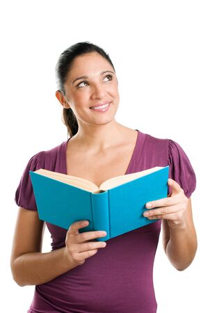 Beautiful young dreaming woman looking up while reading a bookの写真素材