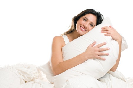 Young woman embracing her pillow in the morning isolated on white backgroundの写真素材