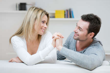 Young couple taking hands each other with love in their living roomの写真素材