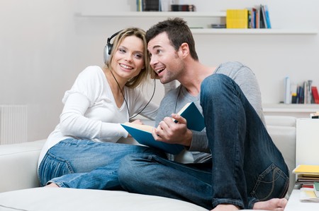 Young couple relaxing and listening music together in their living room at homeの写真素材