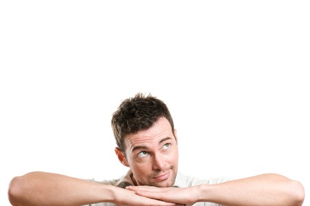 Young smiling man imagine and dreaming looking up at copy space for your text, isolated on white backgroundの写真素材