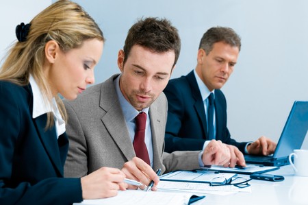 Businessman and businesswoman examining together a document during a working meeting in officeの写真素材