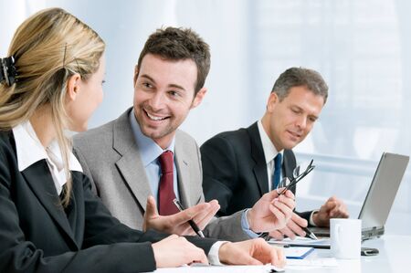 Happy smiling businessman cheering at new success with his business team at officeの写真素材