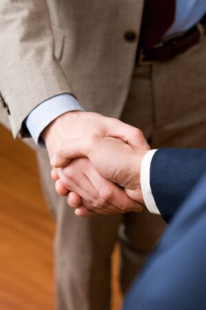 Two professional businessman giving handshake in the office, vertical copy spaceの写真素材