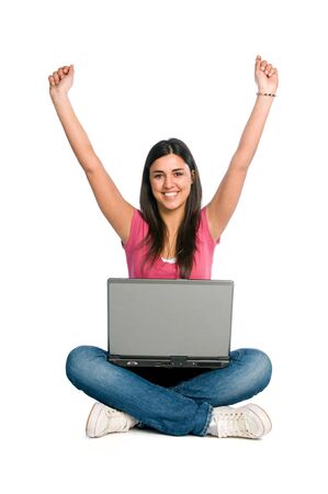 Young happy beautiful woman raised the arms to celebrate in front of her laptop isolated on white backgroundの写真素材