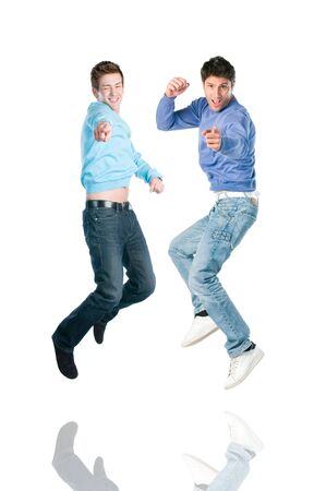 Two young happy jumping men pointing at you with index fingerの写真素材