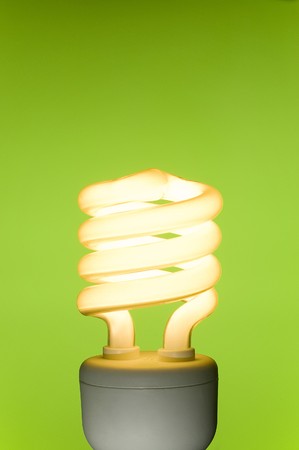 Energy saving fluorescent light bulb on green background. Space for text.の写真素材