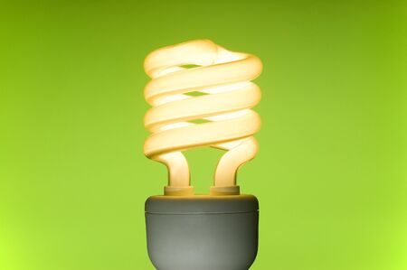 Energy saving fluorescent light bulb on green background. Space for text.の写真素材