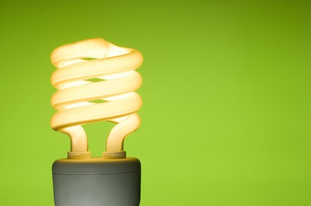 Energy saving fluorescent light bulb on green background. Space for text.の写真素材