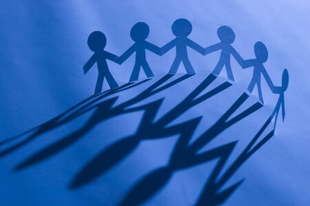 Paper man chain holding hands on blue. Symbol of unity, brotherhood and teamworkの写真素材