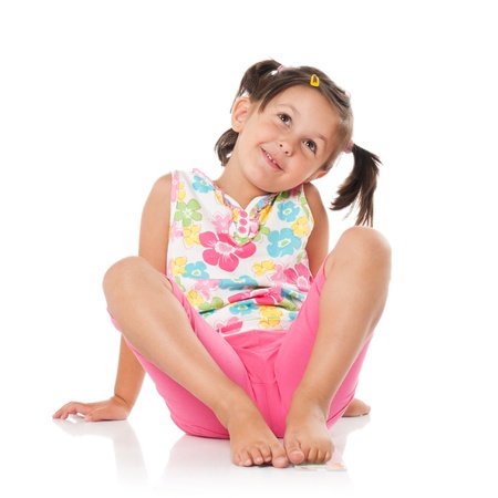 Smiling little girl imaging and sitting on floor isolated on white backgroundの写真素材