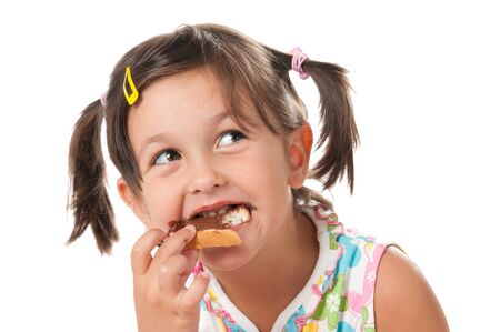 Happy little girl bite a snack of chocolate spread isolated on white backgroundの写真素材