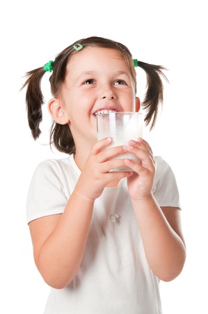 Happy smiling little girl drinking a glass of milk isolated on white backgroundの写真素材