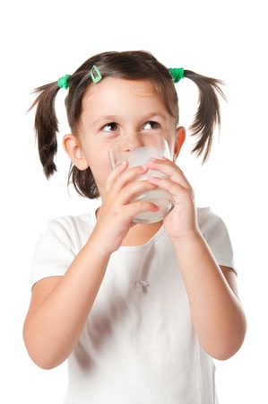 Happy little girl drinking a glass of milk isolated on white backgroundの写真素材