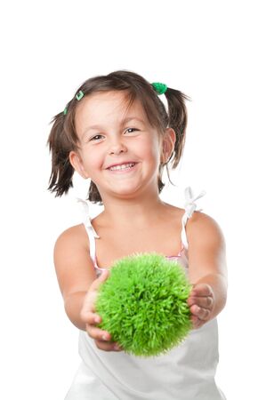 Little girl holding and offering a sphere of green grass, symbol of environmental conservation and responsibility, isolated on white backgroundの写真素材