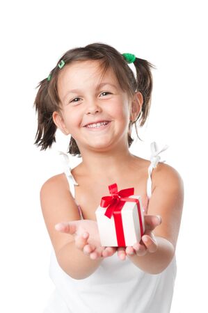 Happy smiling little girl holding and offering a gift for Christmas and birthday isolated on white backgroundの写真素材