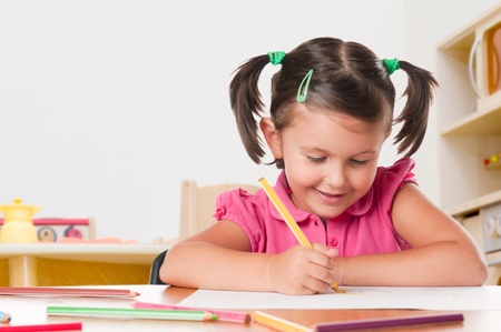 Happy little girl drawing with pencils at homeの写真素材