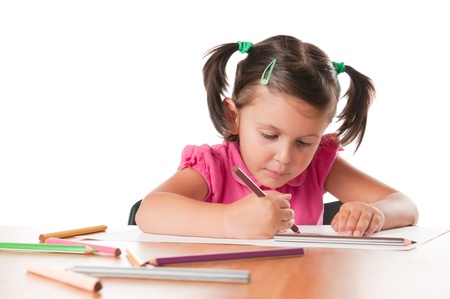 Absorbed little girl drawing with colorful pencils isolated on white backgroundの写真素材