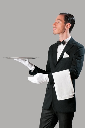 Haughty waiter holding an empty tray to place your productの写真素材