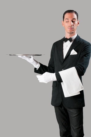 Haughty waiter holding an empty tray to place your productの写真素材