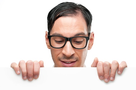 Happy nerd holding white placard for your text and looking down at it isolated on white backgroundの写真素材