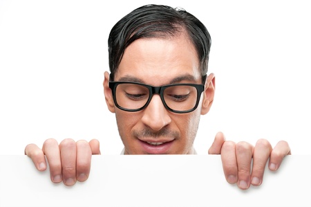 Happy nerd holding white placard for your text and looking down at it isolated on white background