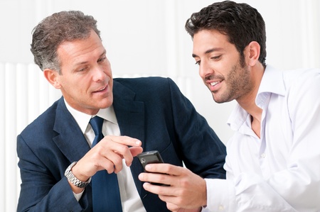 Two businessmen discussing together on a news on a smart phoneの写真素材