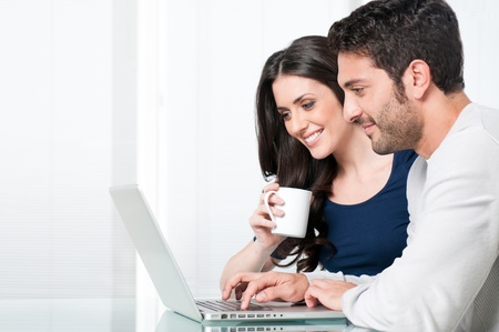 Happy modern couple surfing the net and working on laptop at homeの写真素材