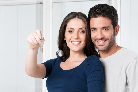 Happy smiling young couple showing a pair of keys of their new houseの写真素材