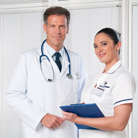 Mature doctor and his female assistant smiling together at hospitalの写真素材